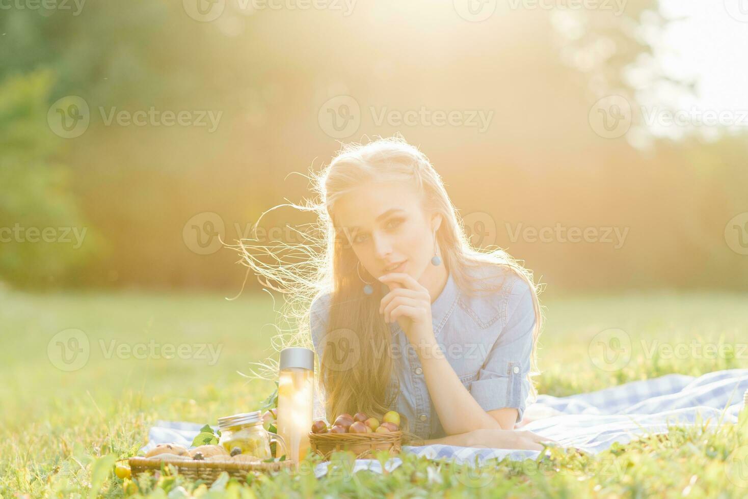 A pretty young woman is resting, lying on a blanket. Summer picnic in the park photo