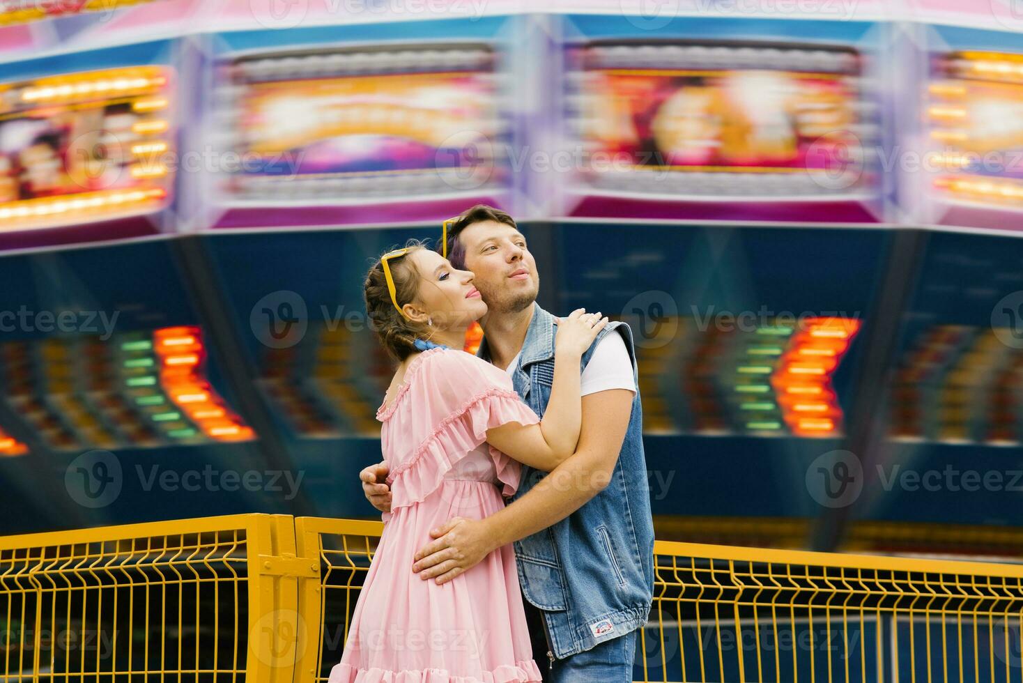 Happy couple in love enjoying each other in an amusement park and cuddling photo