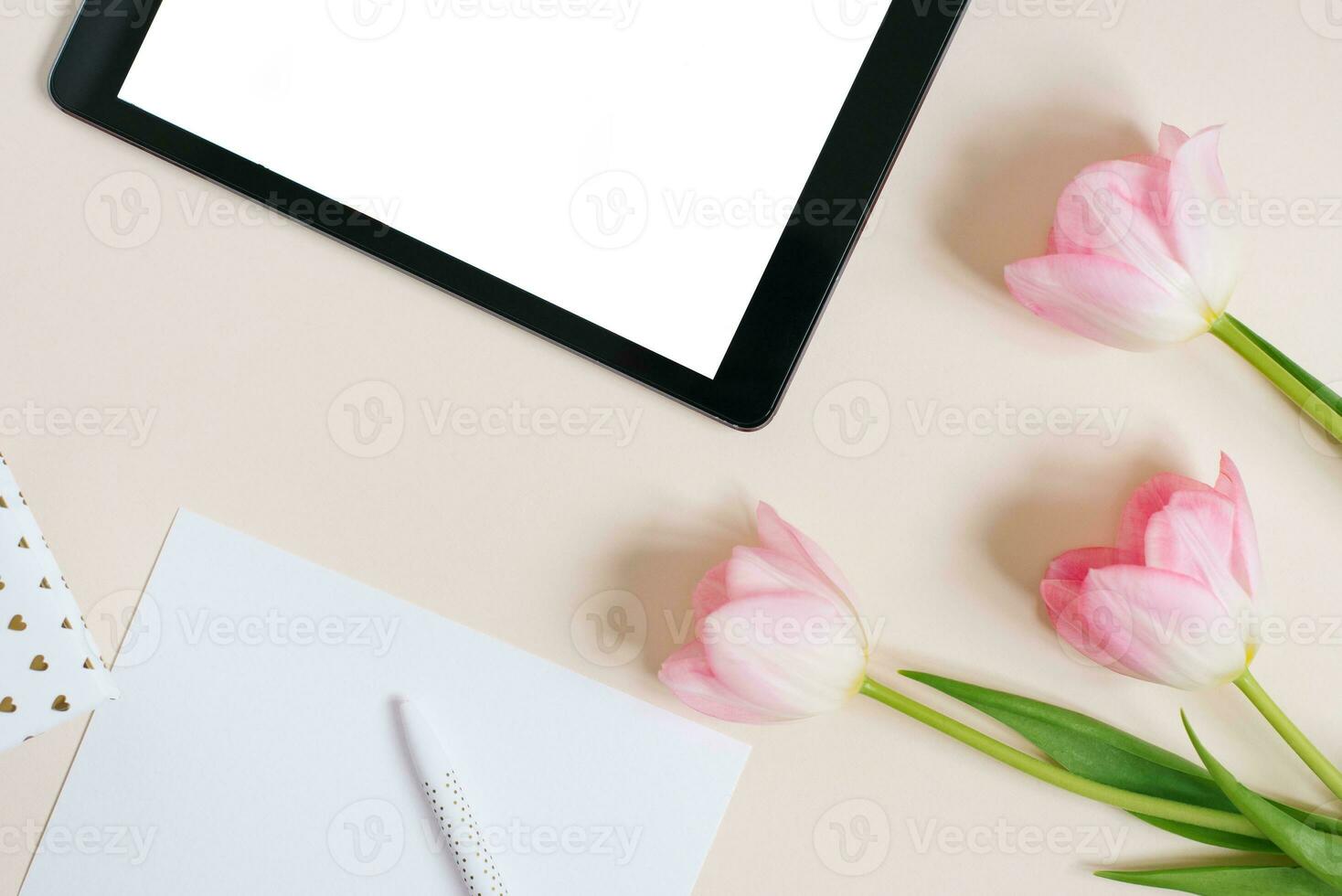 Flat flat top view mock up, digital tablet and pink tulips on beige background. Copy space and flat lay. The concept of the blog for spring, Mother's day, Valentine's day photo
