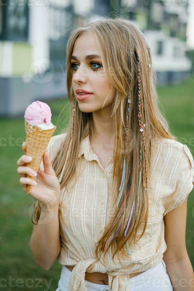 Cute girl eats ice cream from a waffle cone, soiling her lips photo