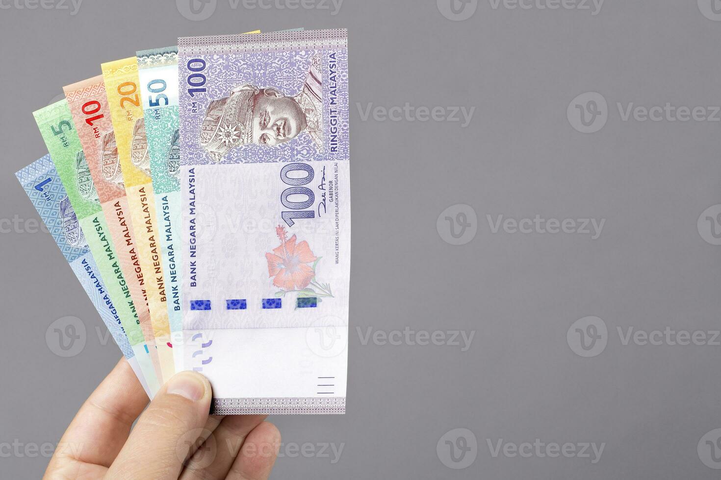 Malaysian ringgit  in the hand on a gray background photo