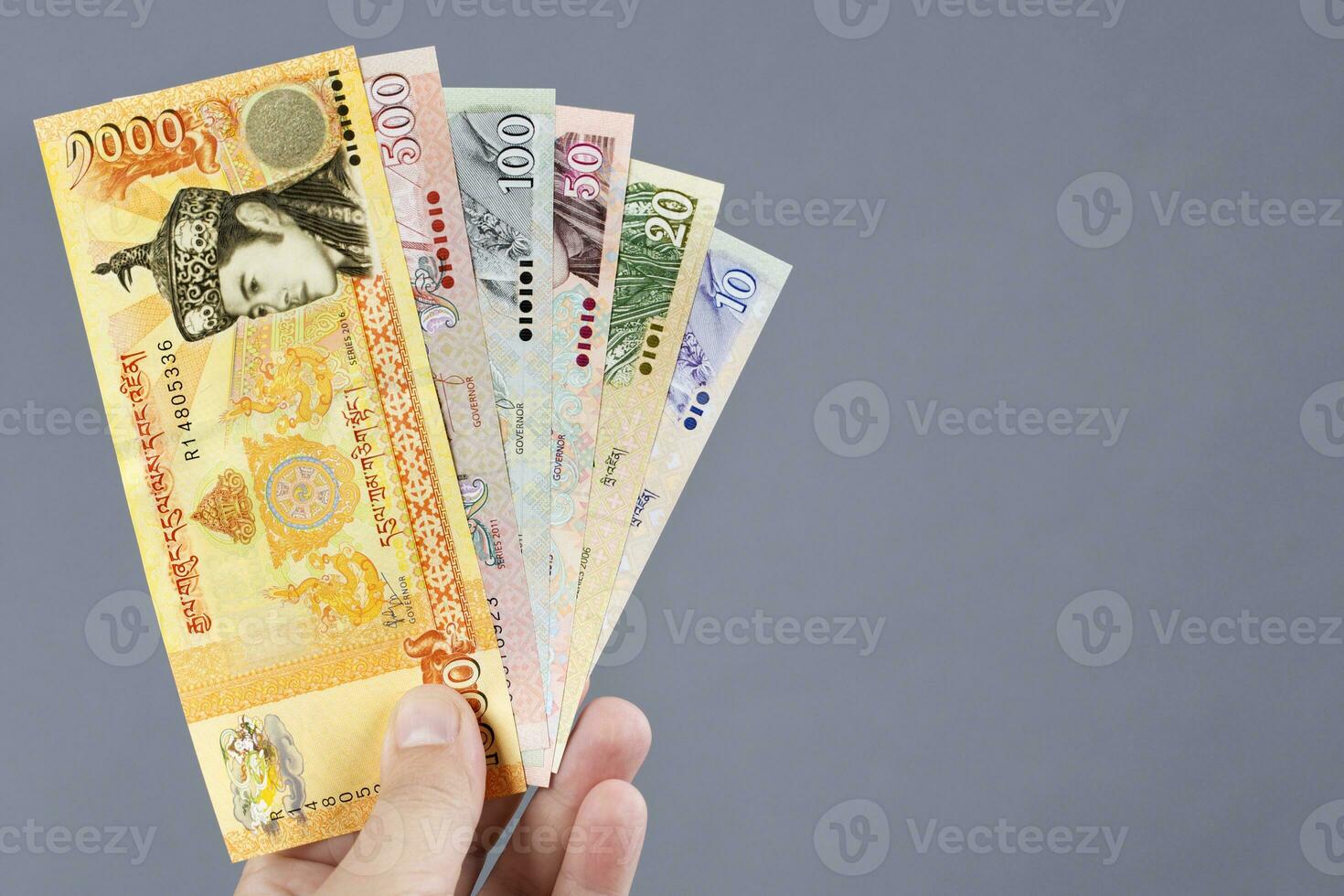 Bhutanese money  in the hand on a gray background photo