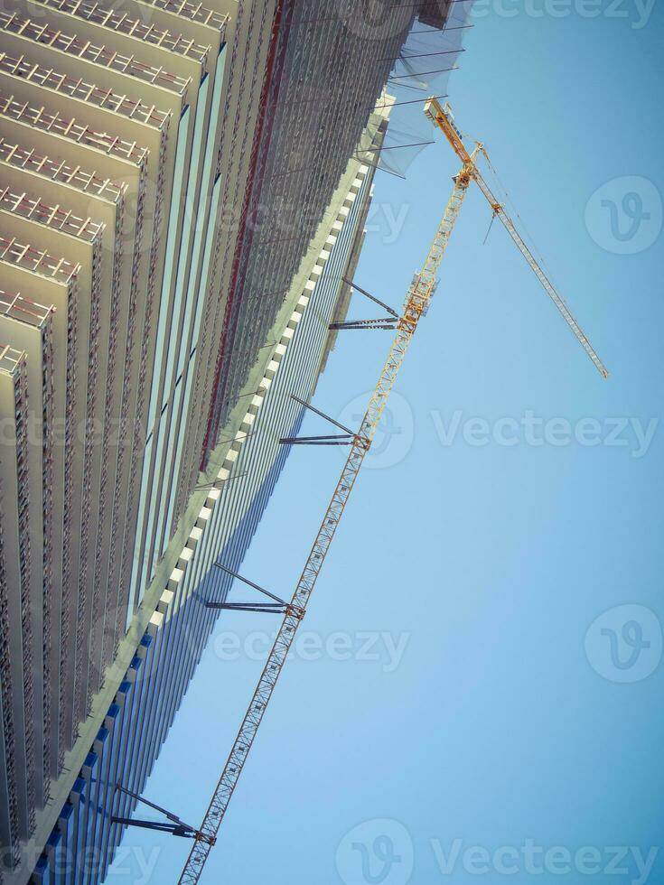 Modern unfinished skyscraper with a lifting crane. photo