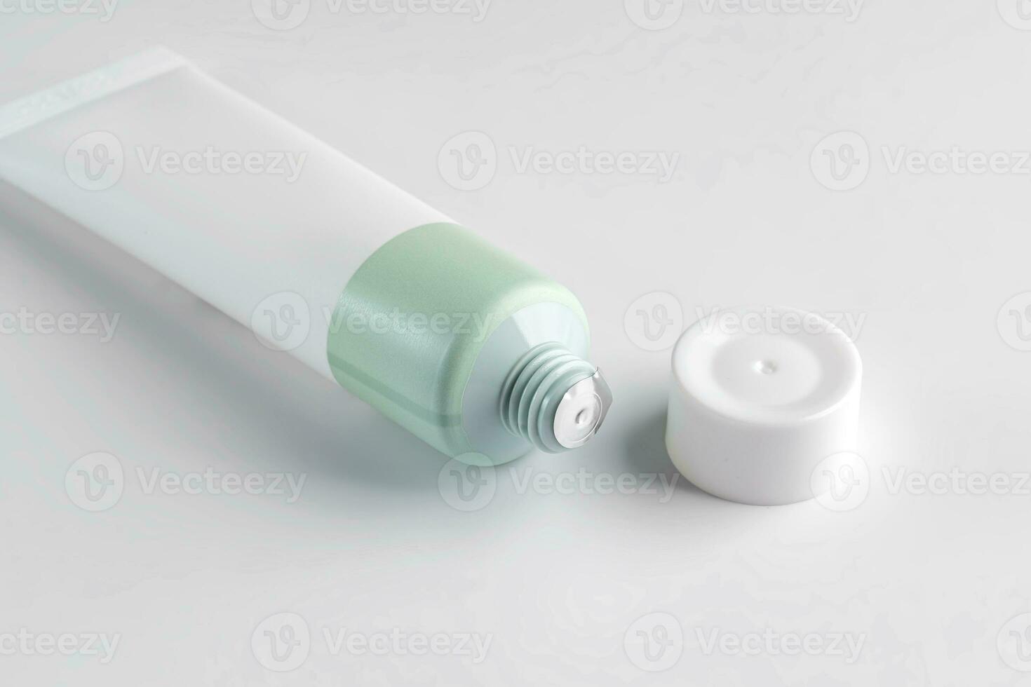 Open tube with cream on white background. Foil membrane for protection. Cosmetics product mockup photo