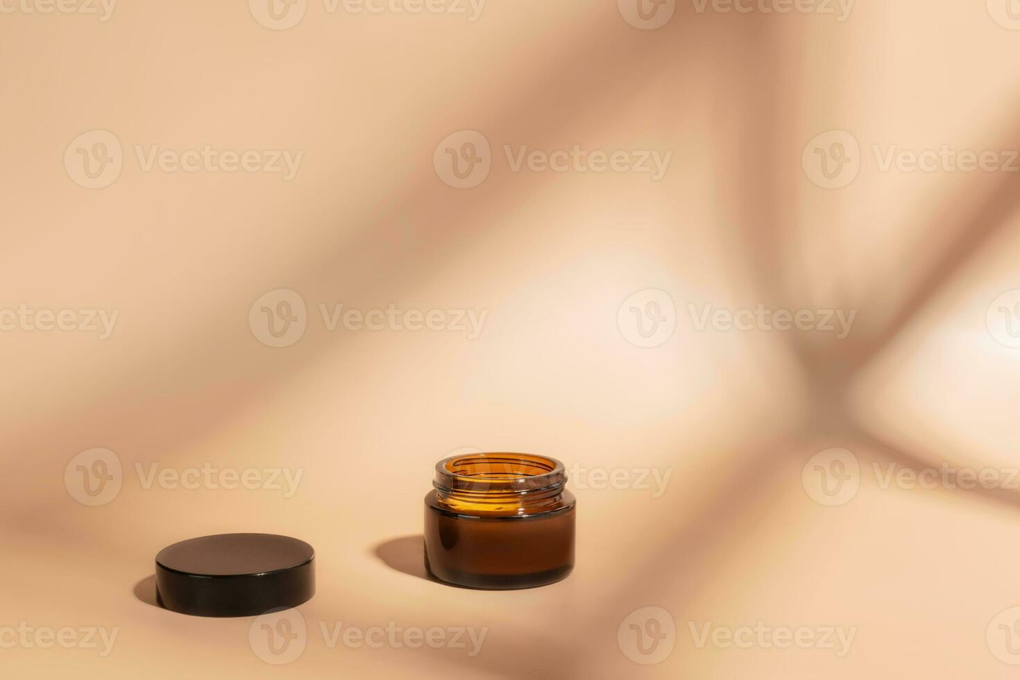 jar of amber glass for cosmetics on brown background with shadow. Mockupsof container with moisturizer for face, hands, close-up. Concept of body care. photo