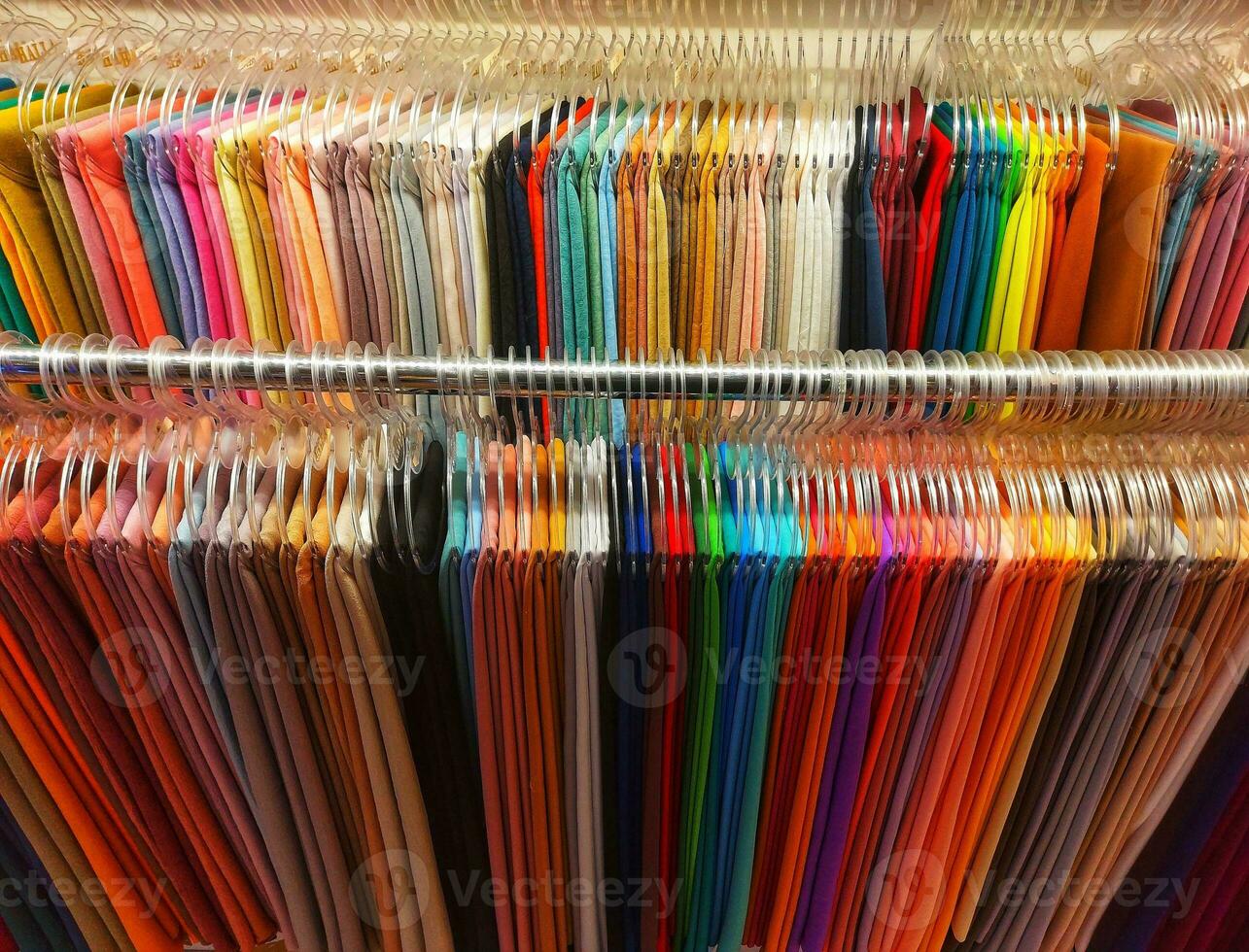 Many variants of the hijab hanging rope model with floral motifs on a white background.there are many variants of the pastel color hanging hijab  using a hanging shelf.a collection of colorful hijabs photo