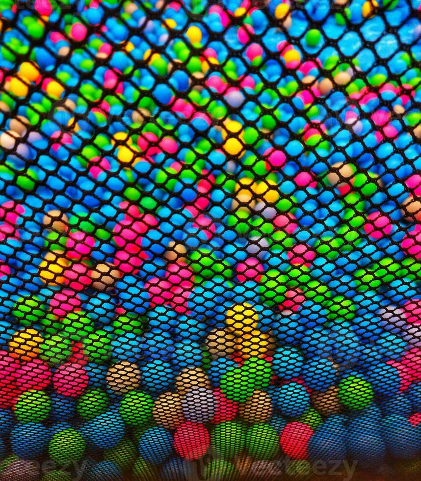 Colored plastic balls are scattered. Lots of multi-Color fun balloons.Many colorful plastic balls in a kids' ballpit at a playground. Close up pattern photo