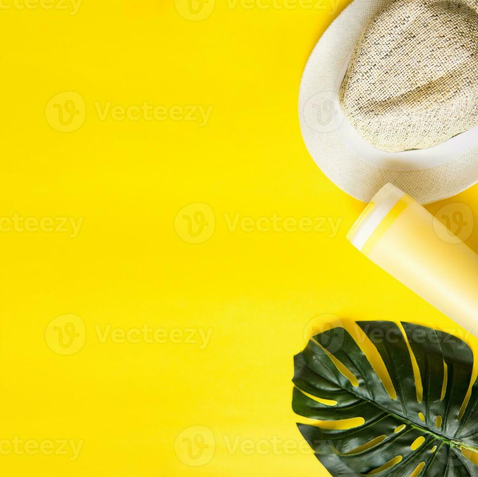 Beach accessories on the yellow background - sunglasses and striped hat. Summer is coming concept.Tropical leaves Monstera. Summer flat lay, top view. Space for text. photo