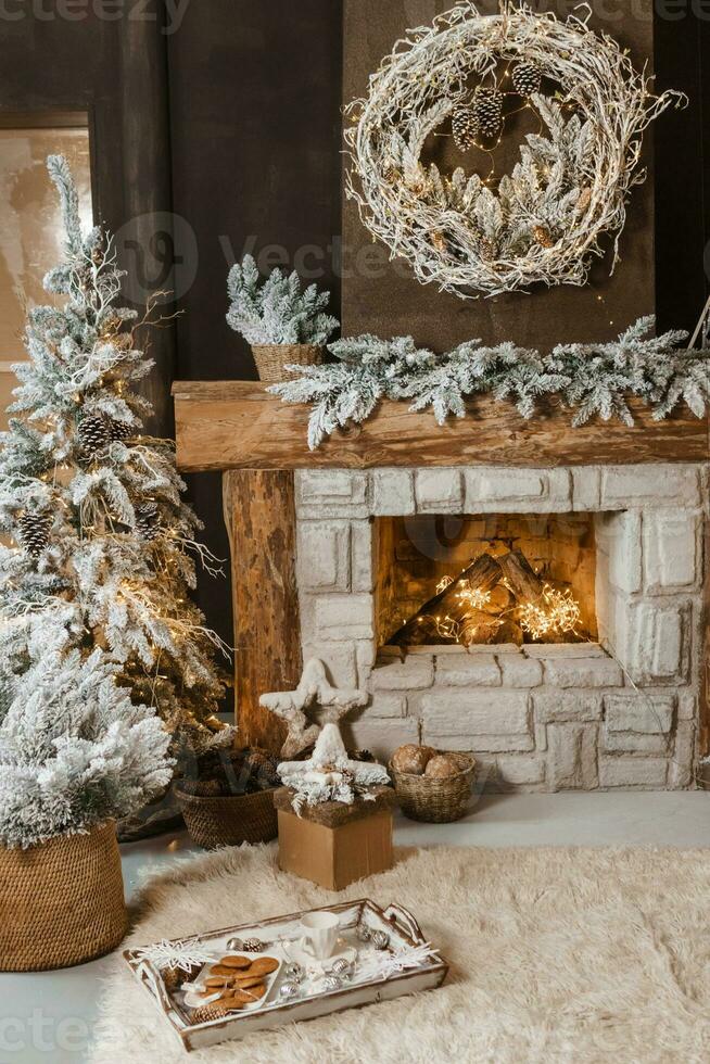 The interior of a room with a fireplace, Christmas trees with artificial snow and garlands, a blanket and a tray with hot drinks. The magical atmosphere of Christmas. photo