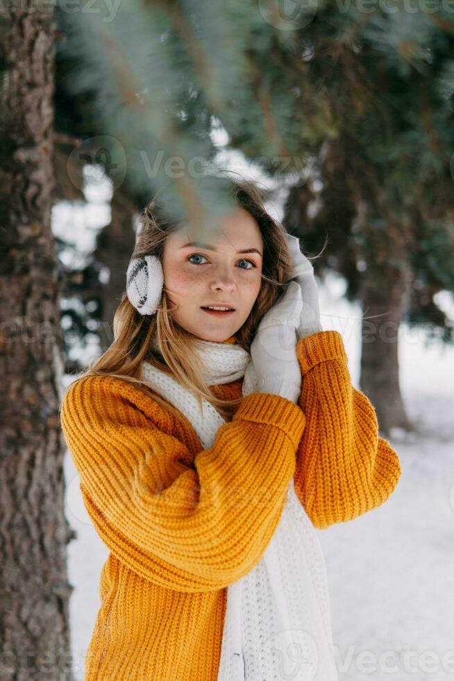 adolescente rubia en un amarillo suéter fuera de en invierno. un Adolescente niña en un caminar en invierno ropa en un Nevado bosque foto