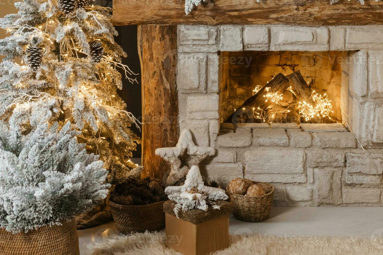 The interior of a room with a fireplace, Christmas trees with artificial snow and garlands, a blanket and a tray with hot drinks. The magical atmosphere of Christmas. photo