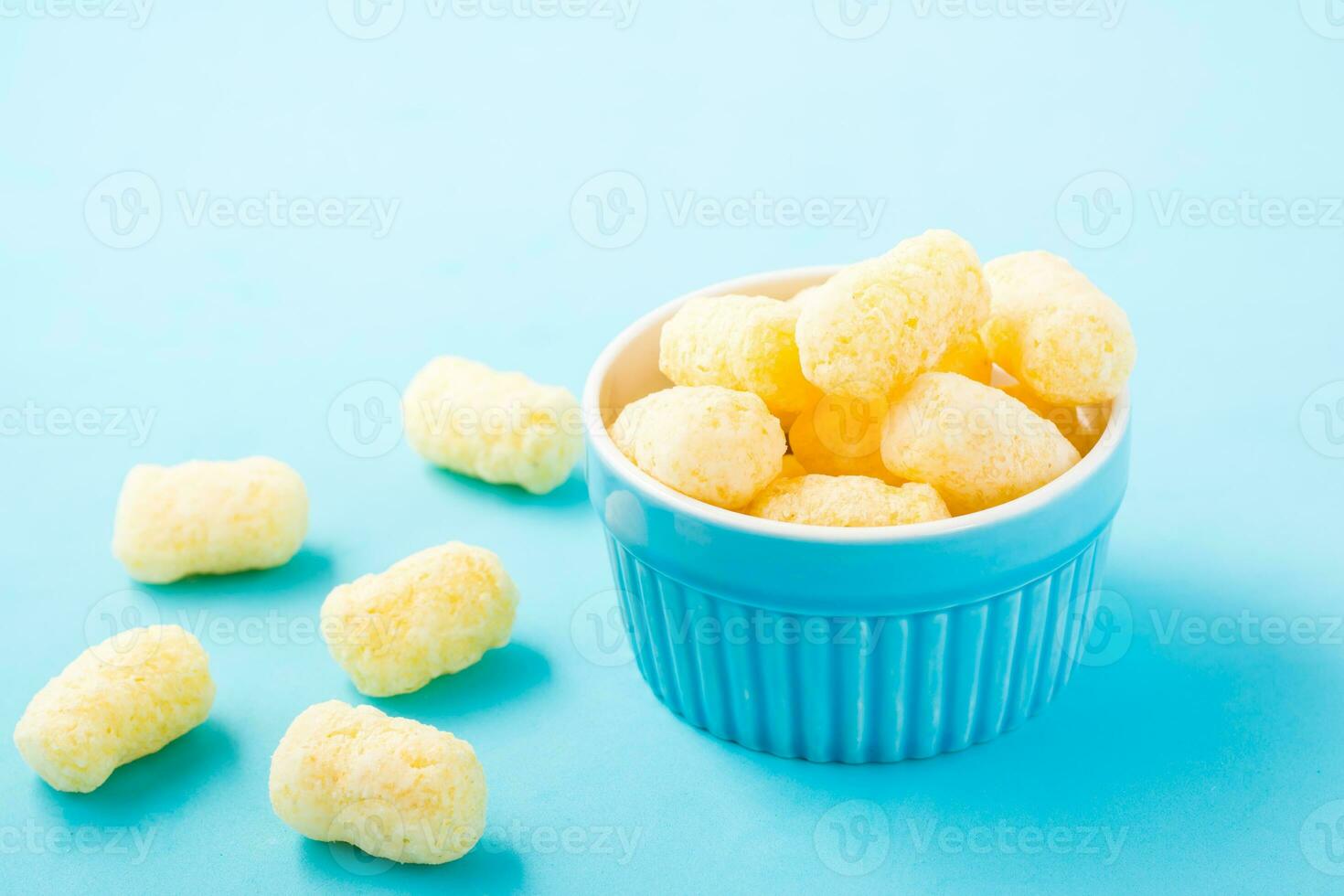 Corn sticks in powdered sugar in a bowl on a blue background. Children treat photo