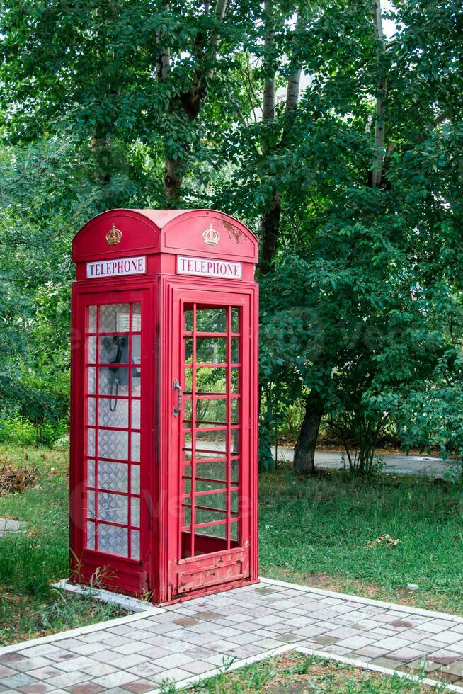 Old vintage red payphone booth on the sidewalk in the street. Outdated communications photo