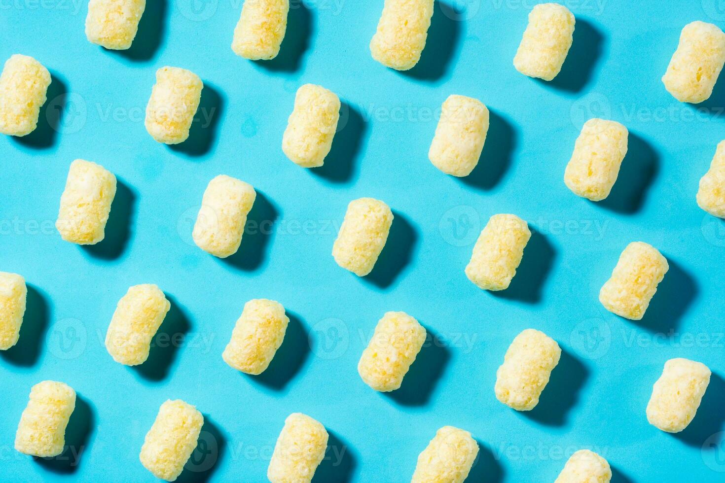 A trendy background of corn sticks on a blue backdrop in harsh light. Top view photo