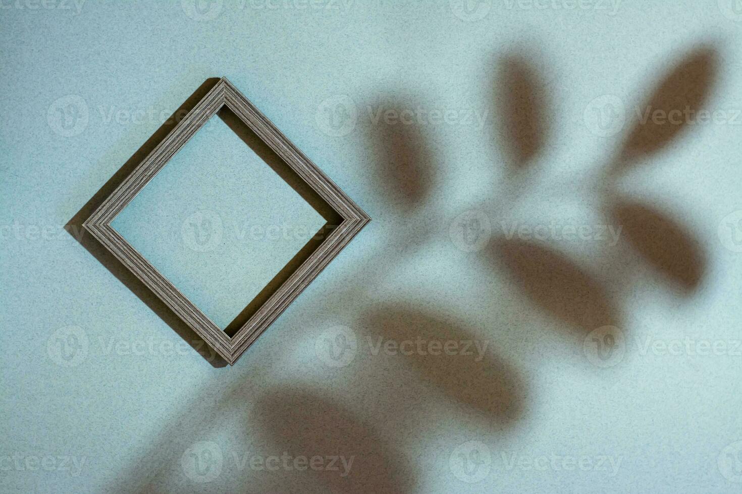 Modern abstract life style background green cardboard and an empty photo frame in soft shadows from a branch with leaves. Top view. Place for text