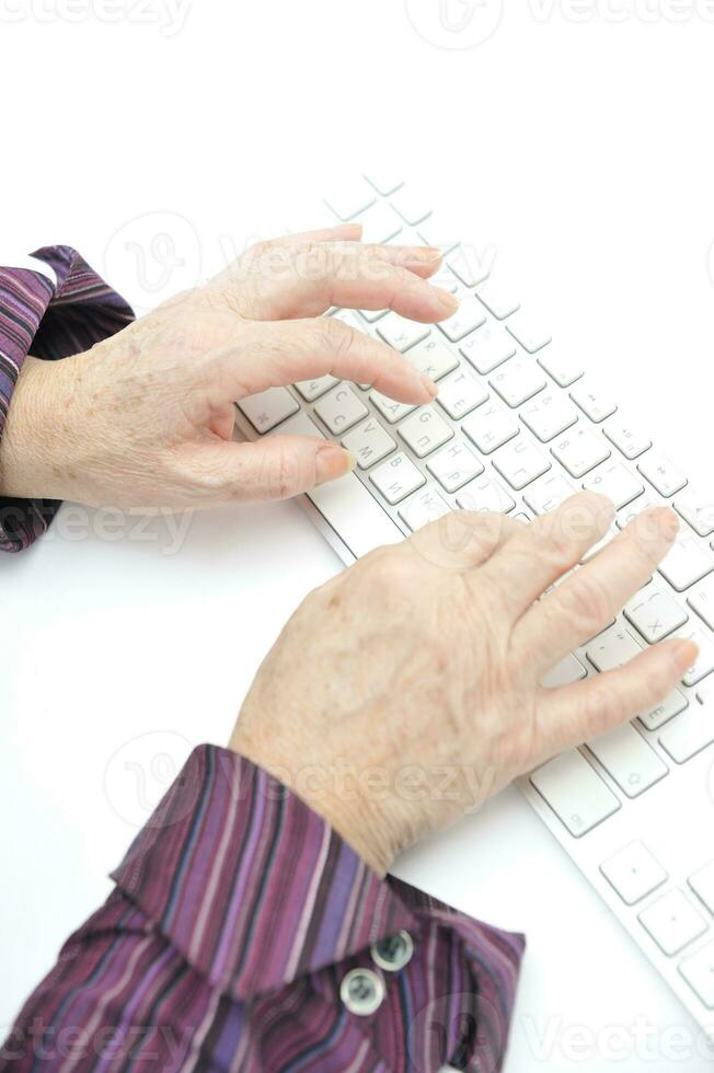 Hands of an old female typing on the keyboard, isolated on white, close-up. photo