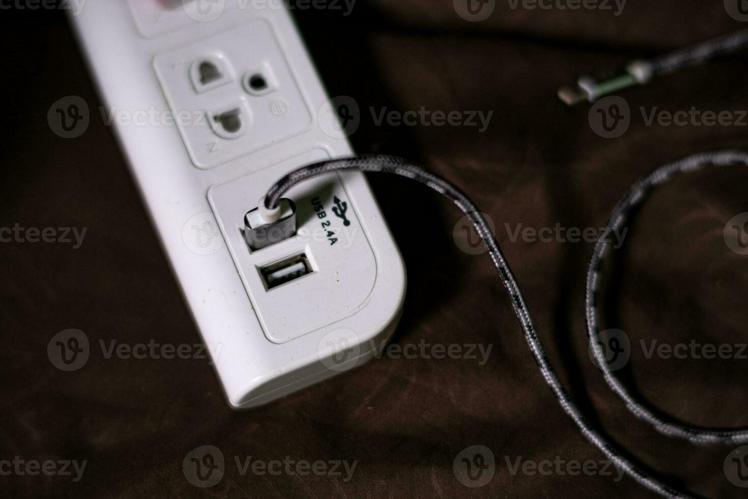 White power socket with black USB charging cable isolated on brown background photo