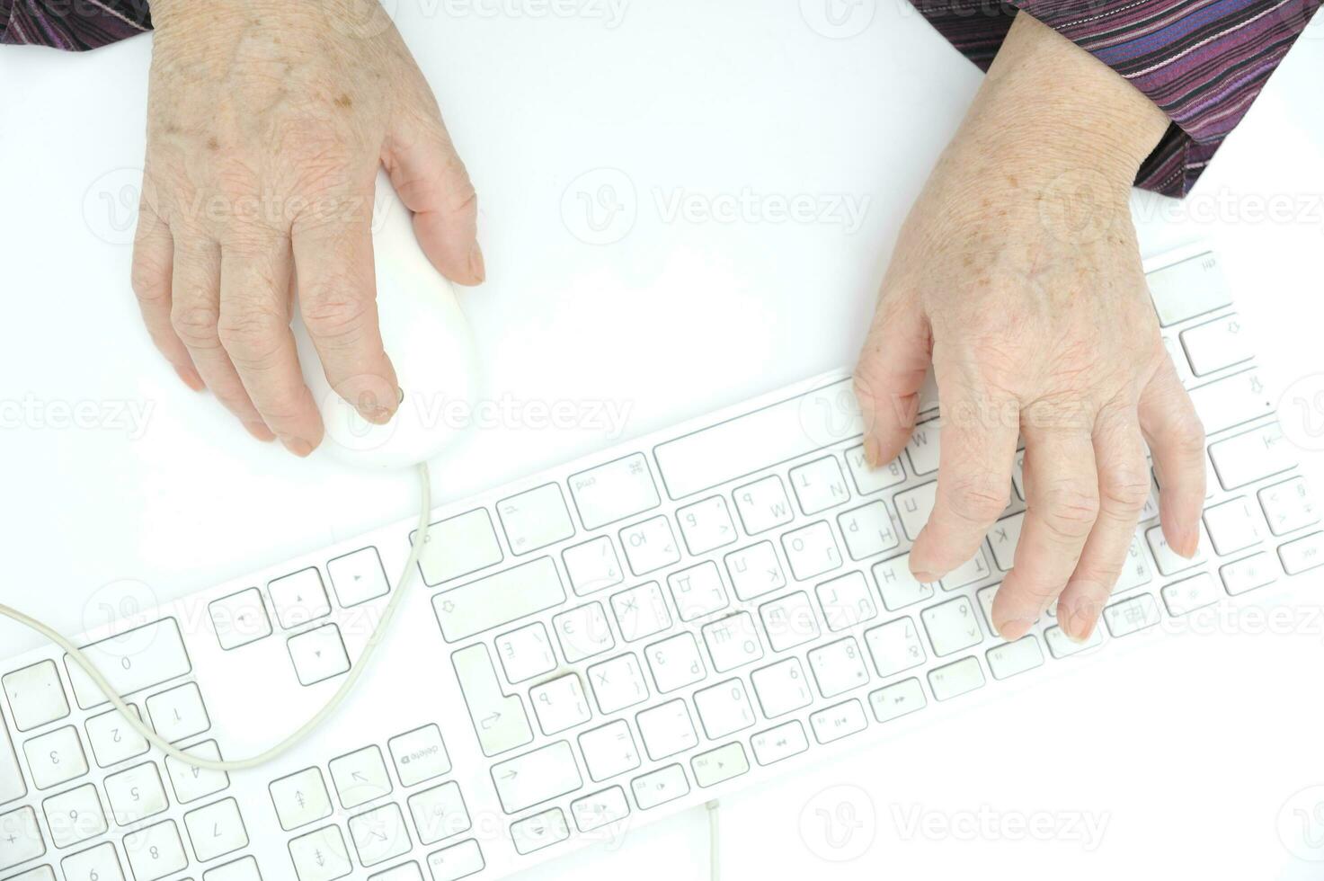 Hands of an old female typing on the keyboard and using mouse, isolated on white, close-up. photo