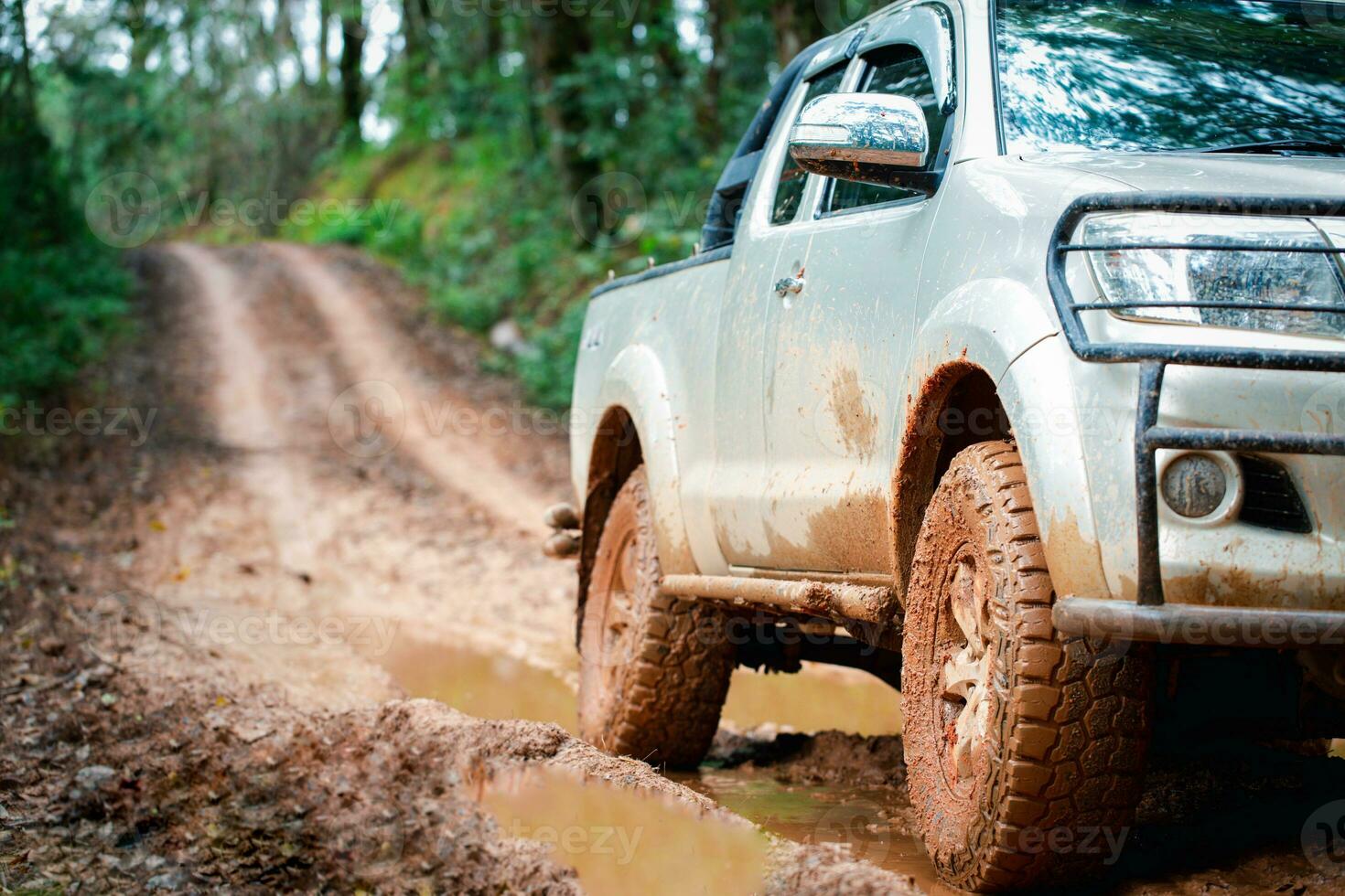 Offroad travel and driving concept, Wheel closeup in a countryside landscape with a muddy road, Off-road travel on muddy road. photo