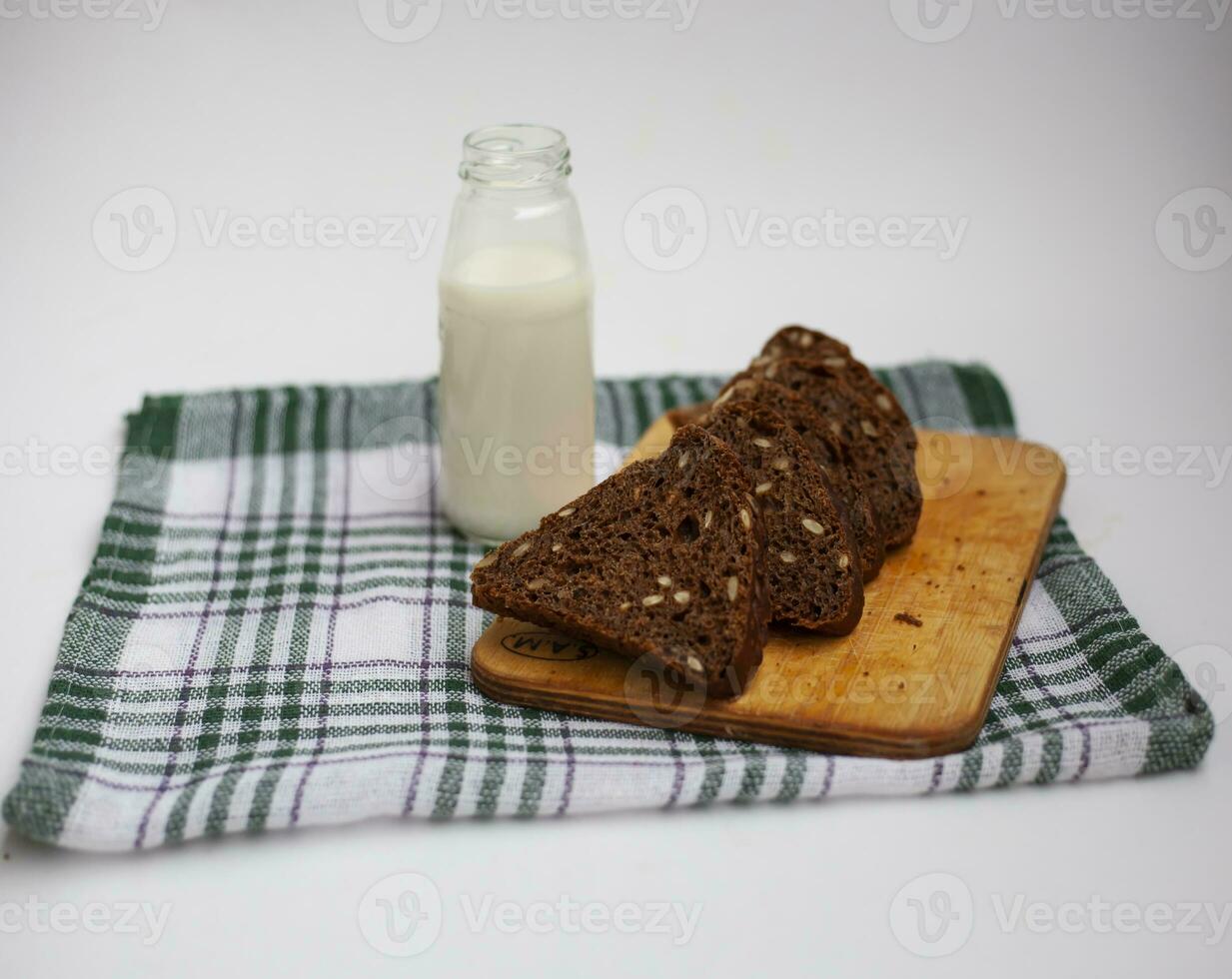 basket of cereal rolls, bagels and slices of rye bread, next to a bottle of milk photo