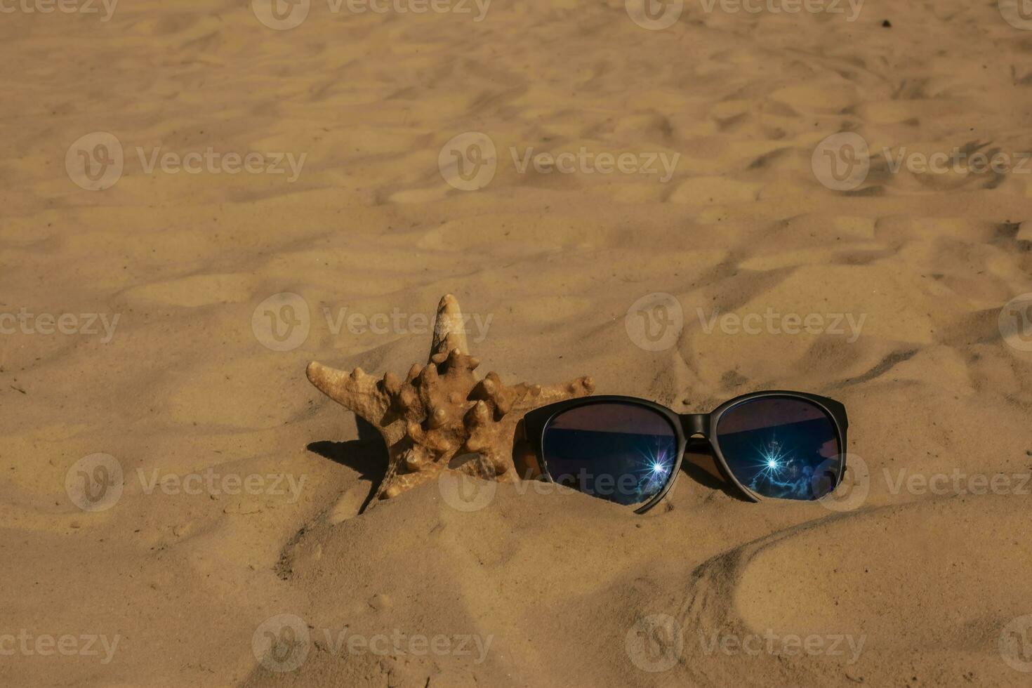 sunglasses lying on tropical sand beach. party. white towel on desk and red glasses with seashells. Sunglasses on the beach. Beautiful sea view wallpaper, background photo