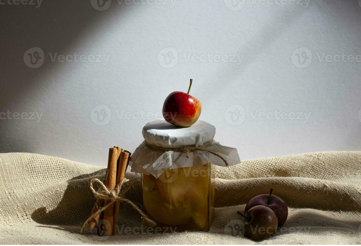 Apple jam in a transparent glass jar. Jam from apples and orange on a light background. Delicious marmalade photo