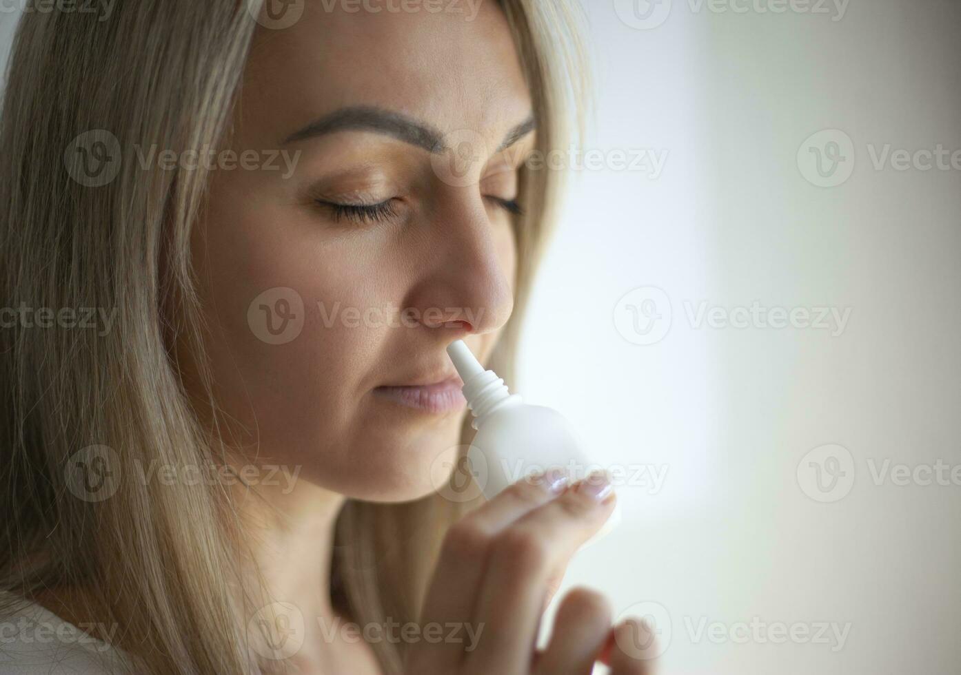 A woman with a runny nose holds a medicine in her hand. photo
