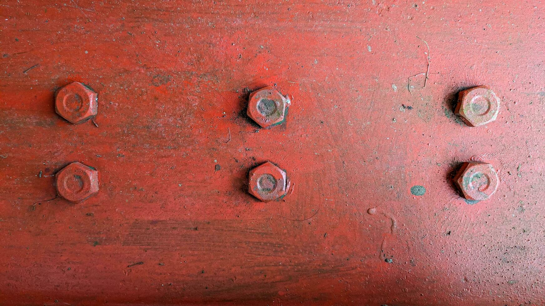 Red metal plate painted steel bolt screws in parallel lines as texture background photo