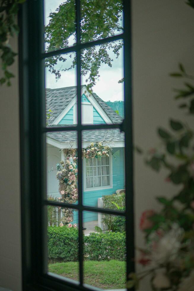 hermosa ver de el acogedor casa con un arqueado Entrada cubierto en rosado y rojo flores foto