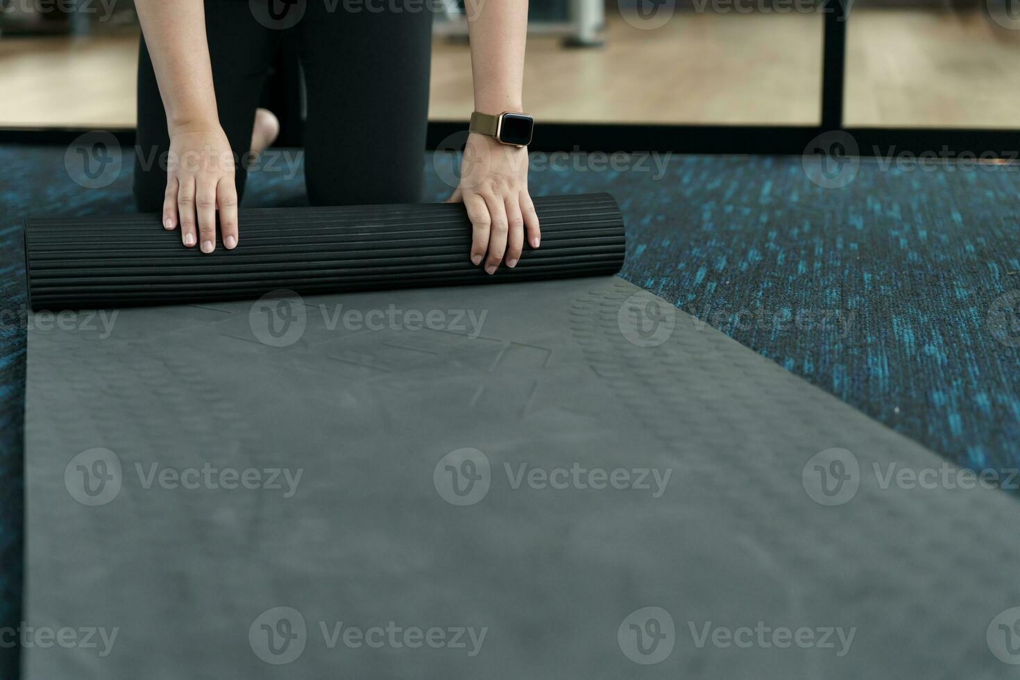 Fitness woman folding exercise mat before working out in yoga studio. rolling Yoga mat  after training healthy lifestyle photo