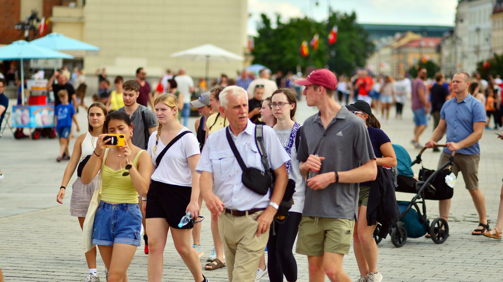 Warsaw, Poland. 29 July 2023. Crowd of people walking on a street. A crowd moving against a background of an urban old city landscape. photo