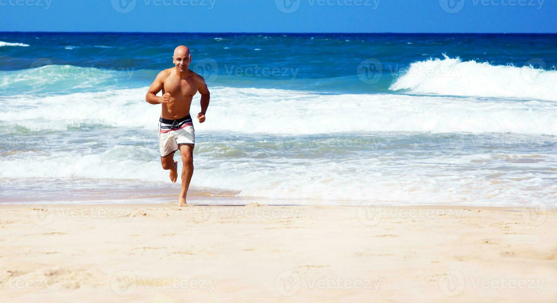 Healthy man running on the beach photo