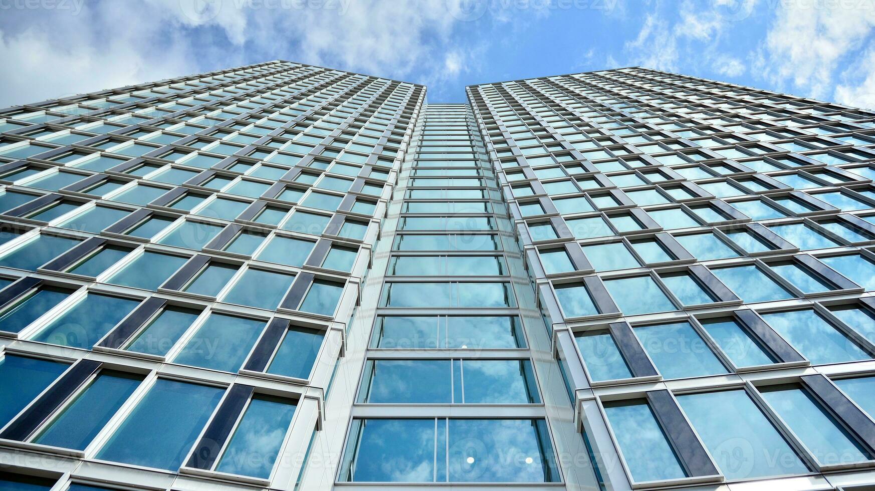 Abstract fragment of contemporary architecture, walls made of glass and concrete. Abstract closeup of the glass-clad facade of a modern building covered in reflective plate glass. photo