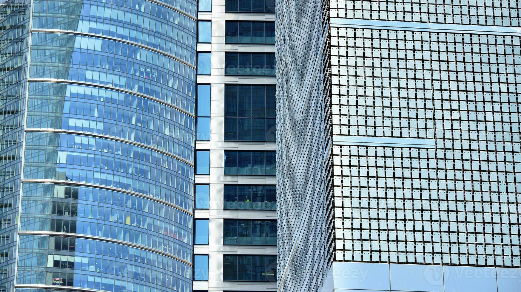 Abstract fragment of contemporary architecture, walls made of glass and concrete. Abstract closeup of the glass-clad facade of a modern building covered in reflective plate glass. photo