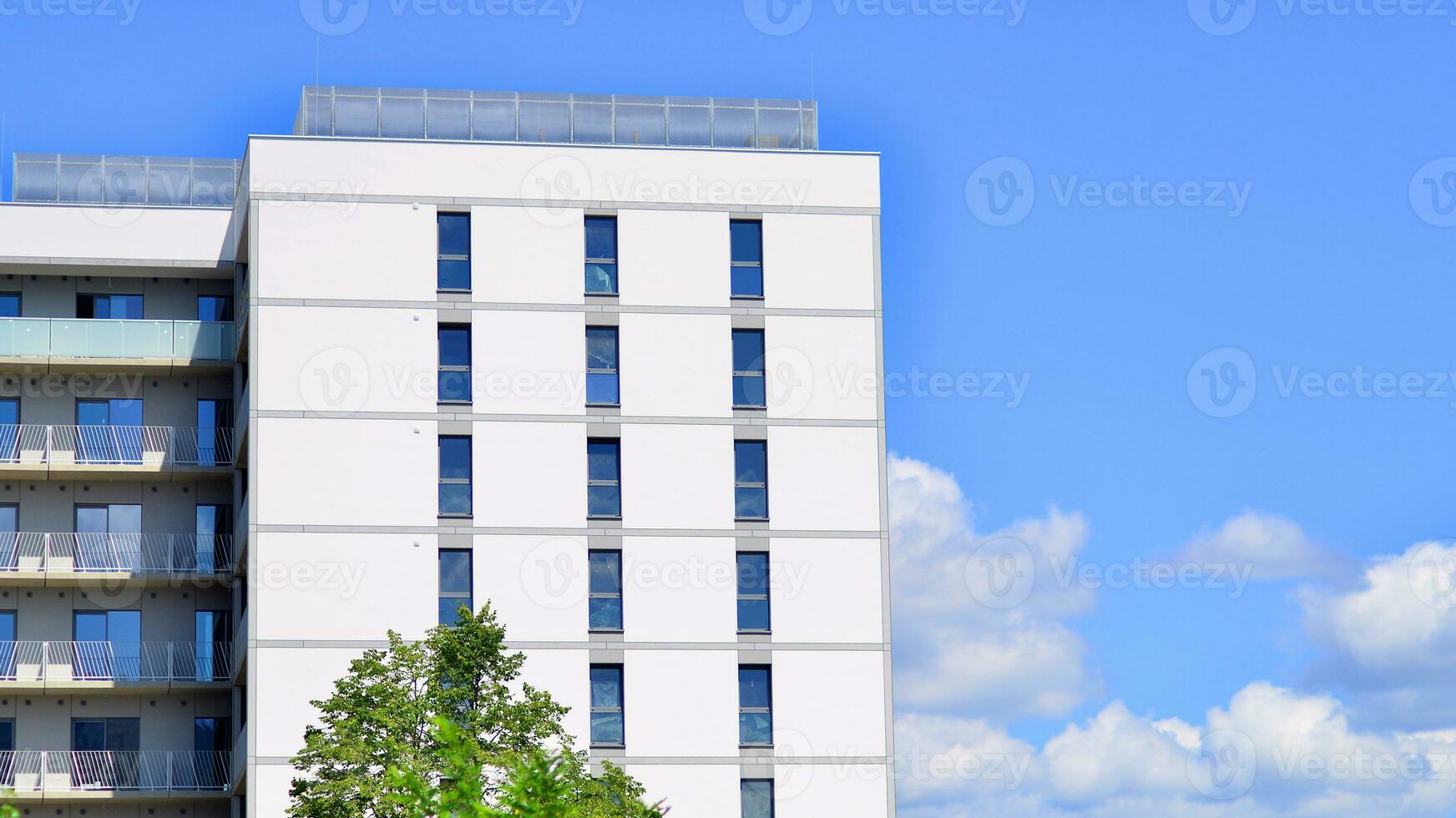 Modern residential building with new apartments in a green residential area. Eco architecture. Green tree and new apartment building. The harmony of nature and modernity. photo
