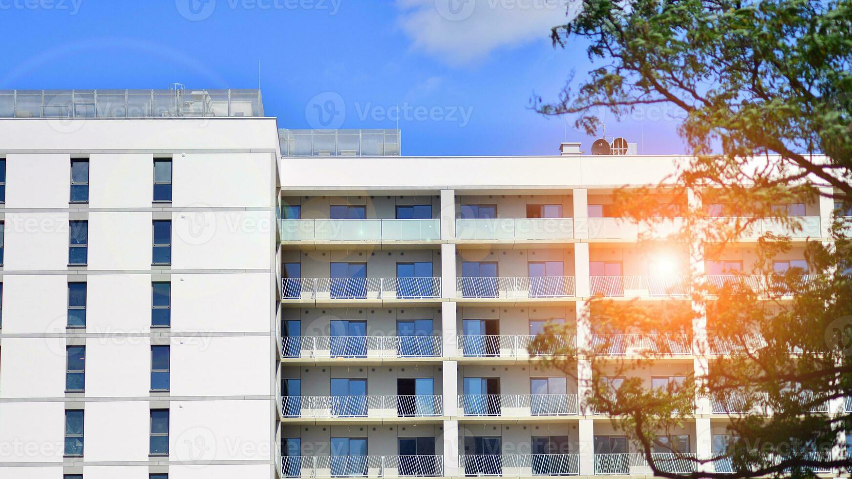 Modern residential building with new apartments in a green residential area. Eco architecture. Green tree and new apartment building. The harmony of nature and modernity. photo