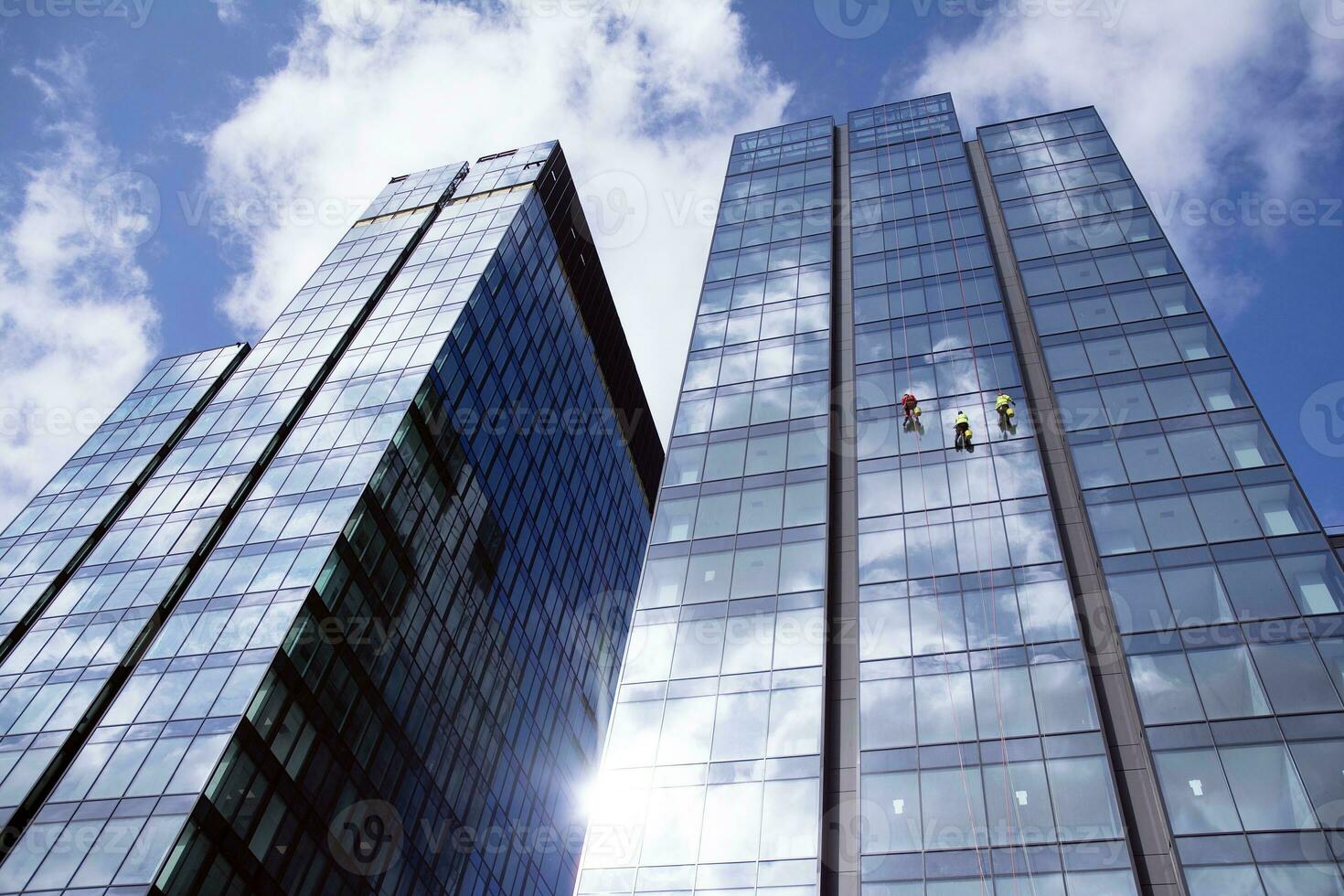 Abstract fragment of contemporary architecture, walls made of glass and concrete. Abstract closeup of the glass-clad facade of a modern building covered in reflective plate glass. photo