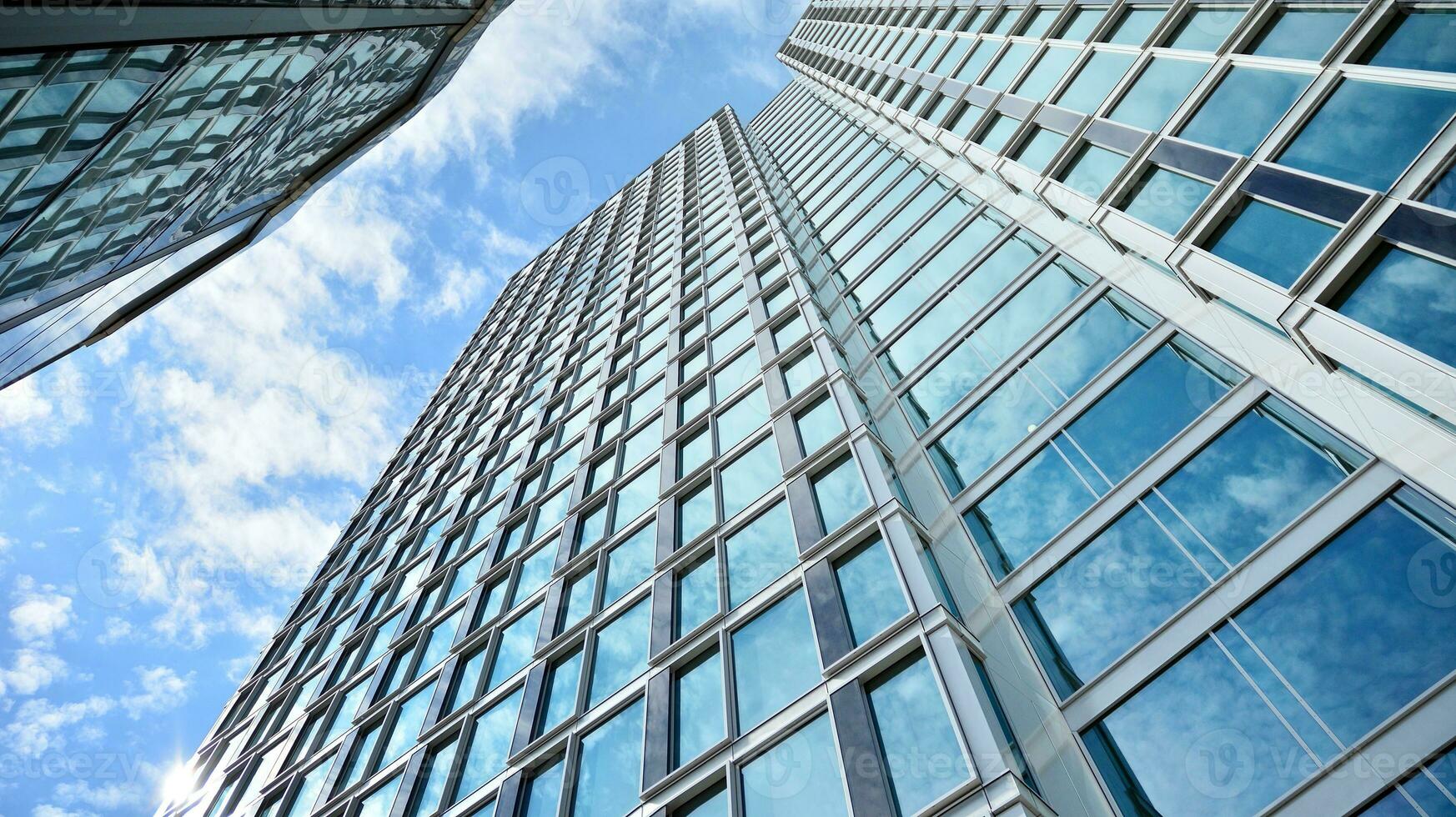 Abstract fragment of contemporary architecture, walls made of glass and concrete. Abstract closeup of the glass-clad facade of a modern building covered in reflective plate glass. photo