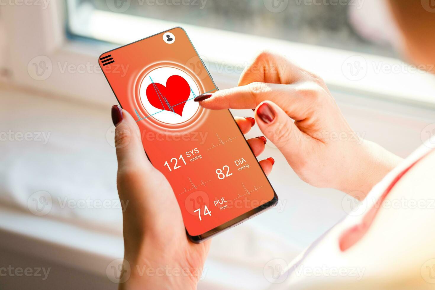 woman sitting on the sofa and holding a phone with app for health card monitoring photo