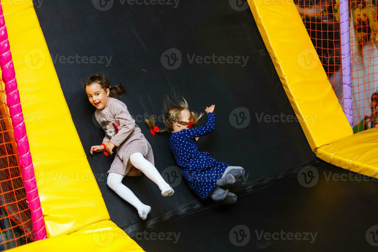 Child jumping on colorful playground trampoline. Kids jump in inflatable bounce castle on kindergarten birthday party Activity and play center for young child. Little girl playing outdoors in summer. photo