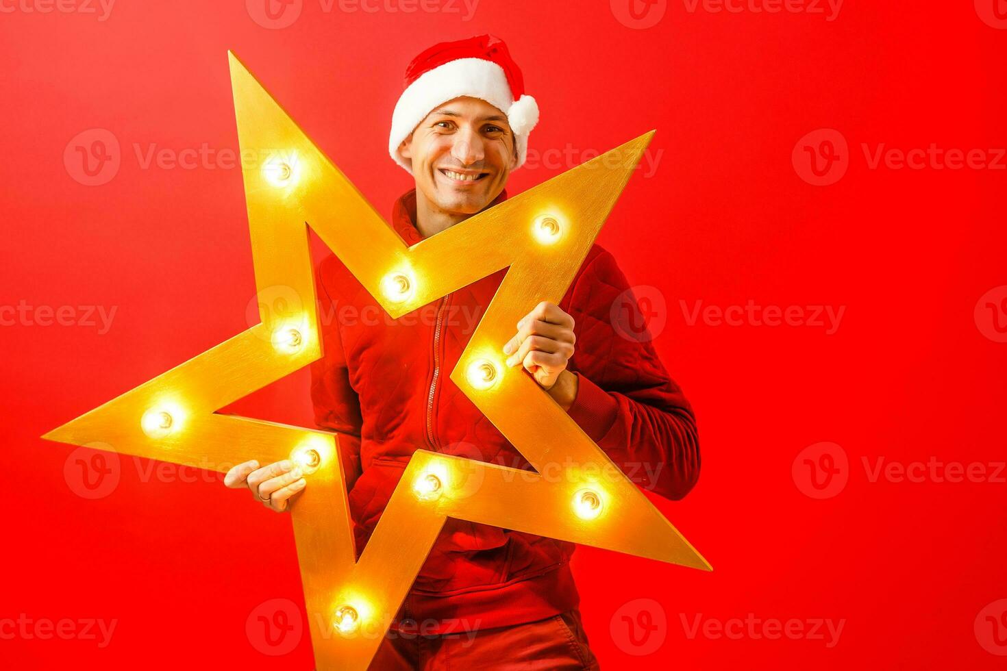 Man in Santa hat decorating facade of house with garland for Christmas photo