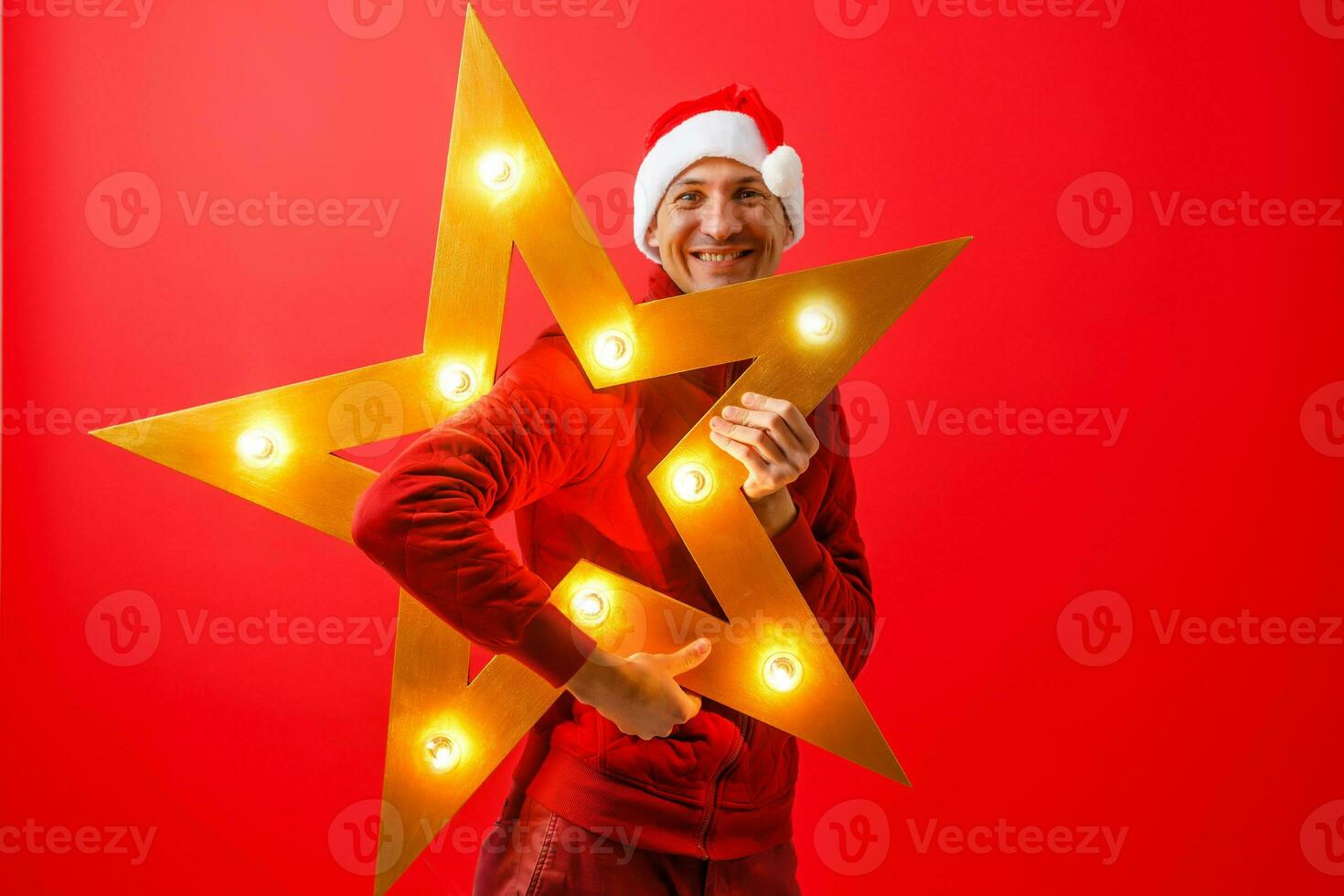 Photo of cheerful man in Santa's cap with Christmas star garland in hands