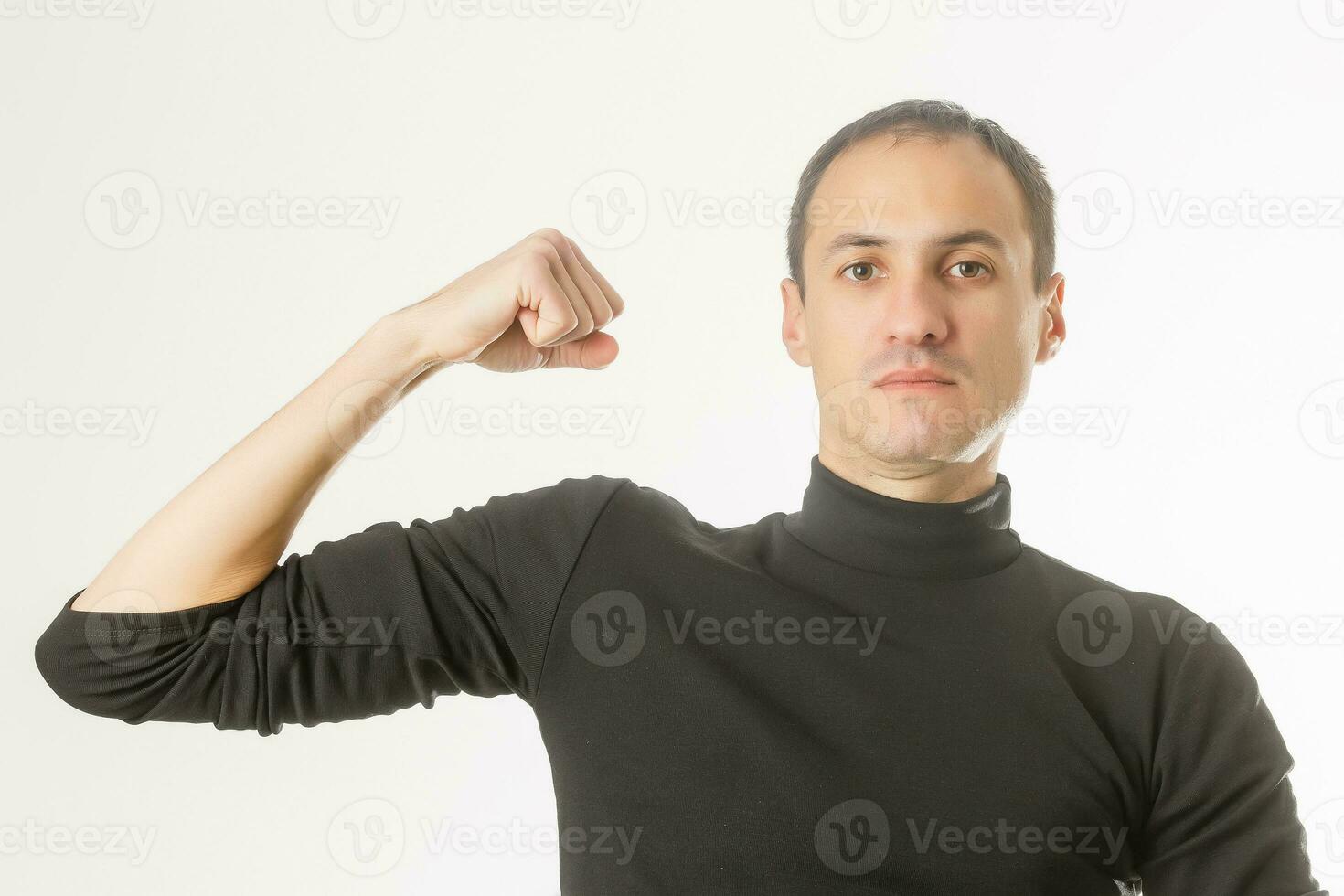 Portrait of young handsome dark-haired man , holding his arm up to show how strong he, isolate white background photo