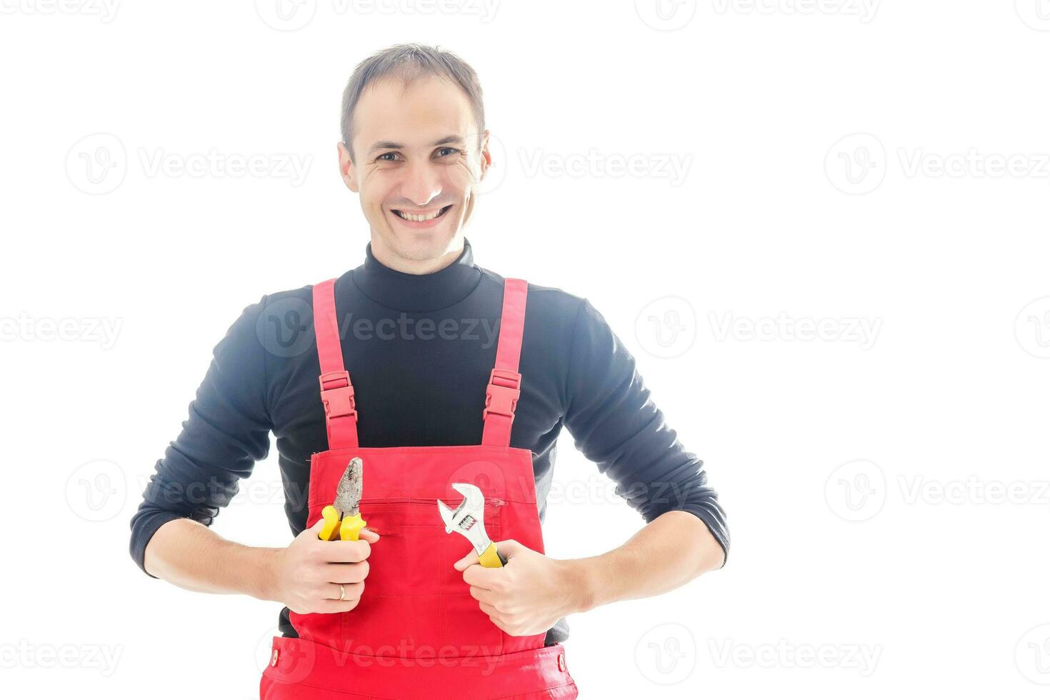 Young mechanic in uniform with crossed arms and wrenches standing, isolated on white photo
