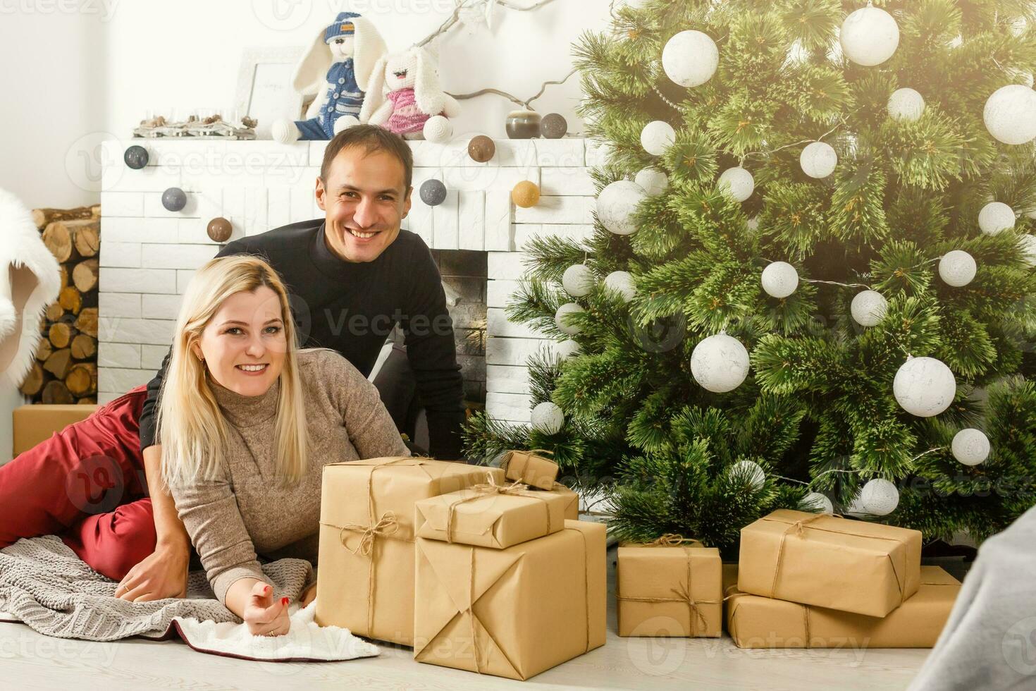 bonito amor Pareja sentado en alfombra en frente de chimenea. mujer y hombre celebrando Navidad foto