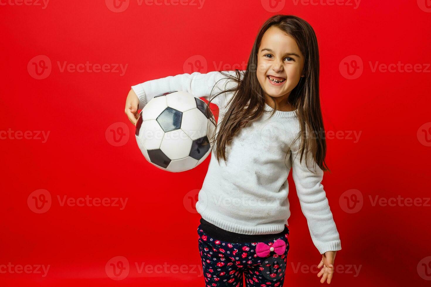 Little girl with the ball over red backgrounf photo