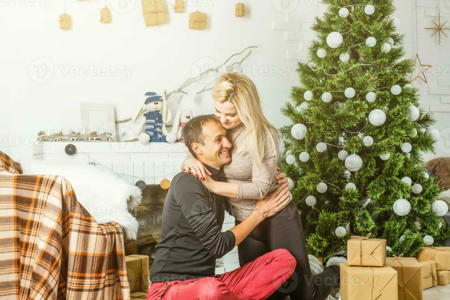 Nice love couple sitting on carpet in front of fireplace. Woman and man celebrating Christmas photo