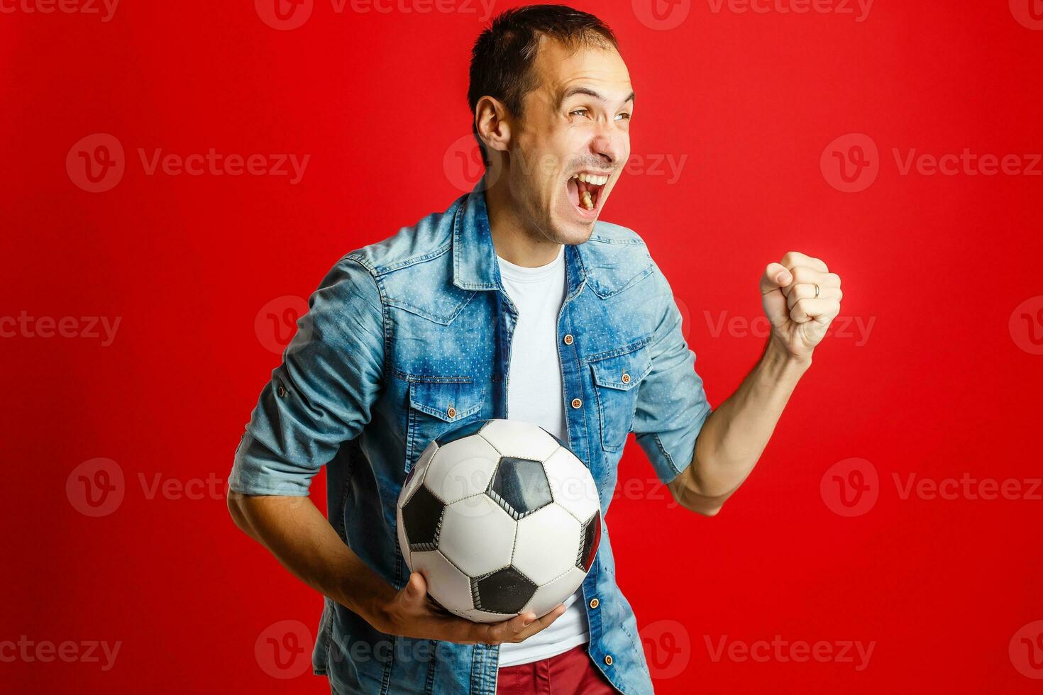 Handsome man holding a soccer ball over red backgound photo