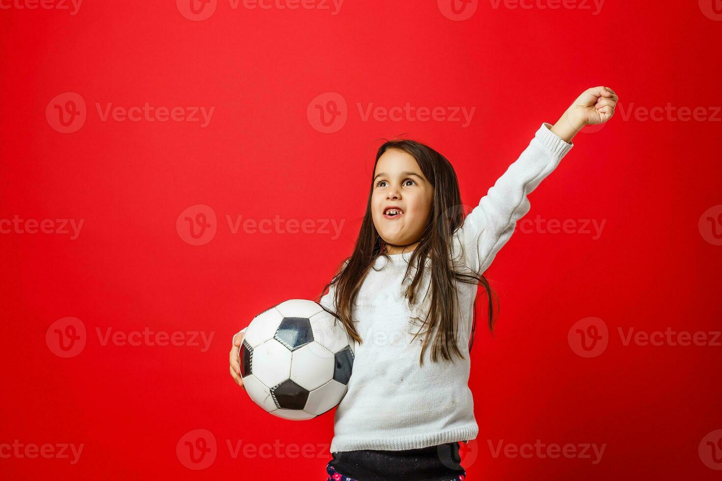 Little girl with the ball over red backgrounf photo