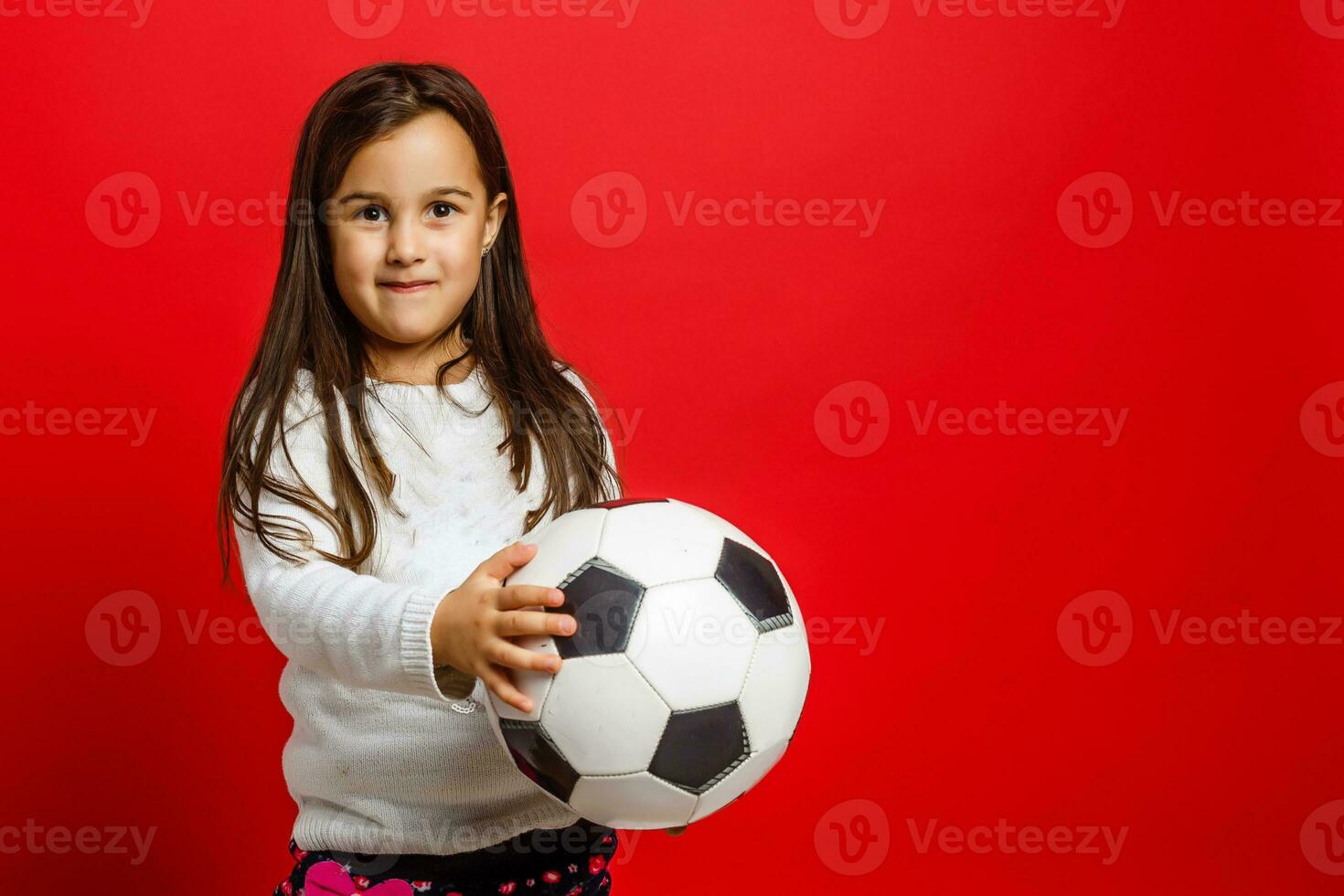 Little young girl with soccer ball in hand smiling on camera isolated on white background photo